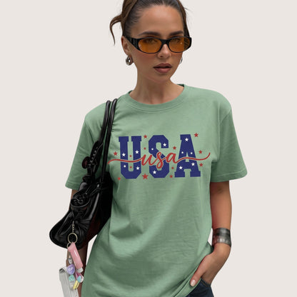 TrendyShift.Com sage green unisex cotton t-shirt with USA patriotic graphic print worn by a woman with sunglasses